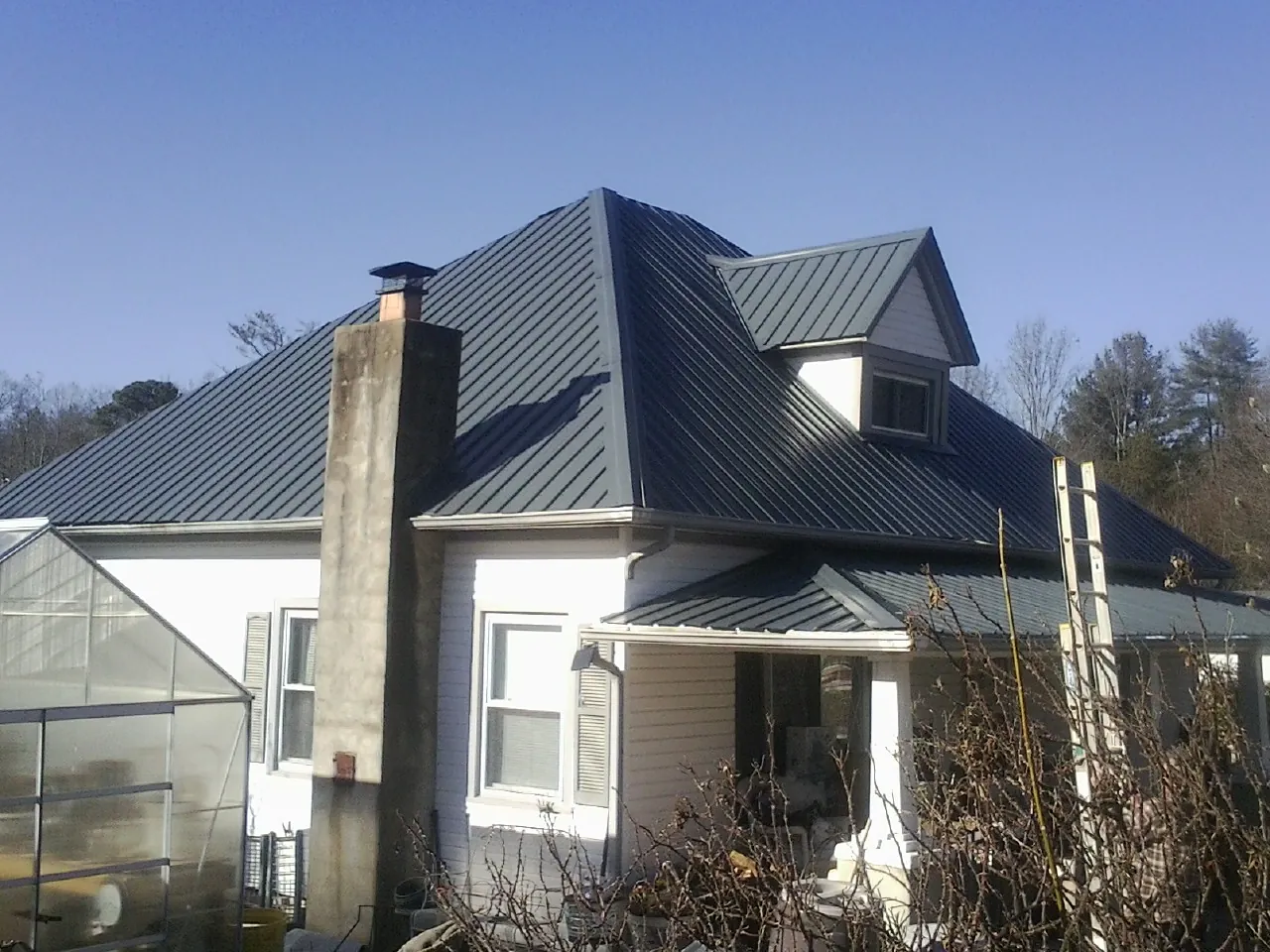 Dark blue standing seam metal roof on a white farmhouse with dormer — Slate & Tile Roof Repair by Roofing Brothers in Marlton