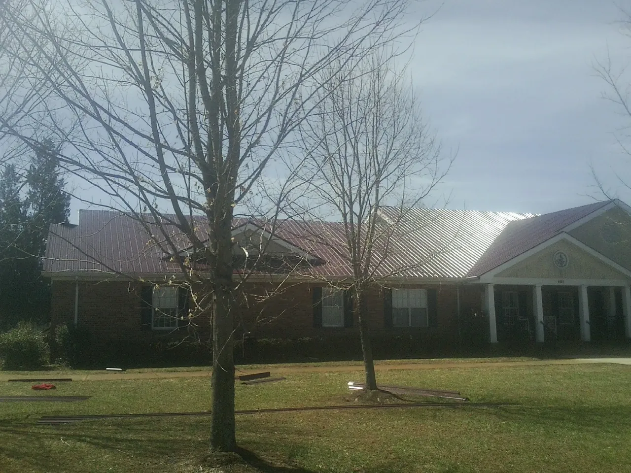 Red metal roof on a brick building seen from the front lawn in Marlton
