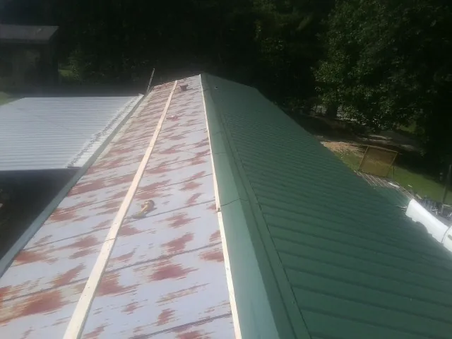 Old rusted panels beside newly installed green metal roofing — Wind Damage Roof Repair by Roofing Brothers in Marlton