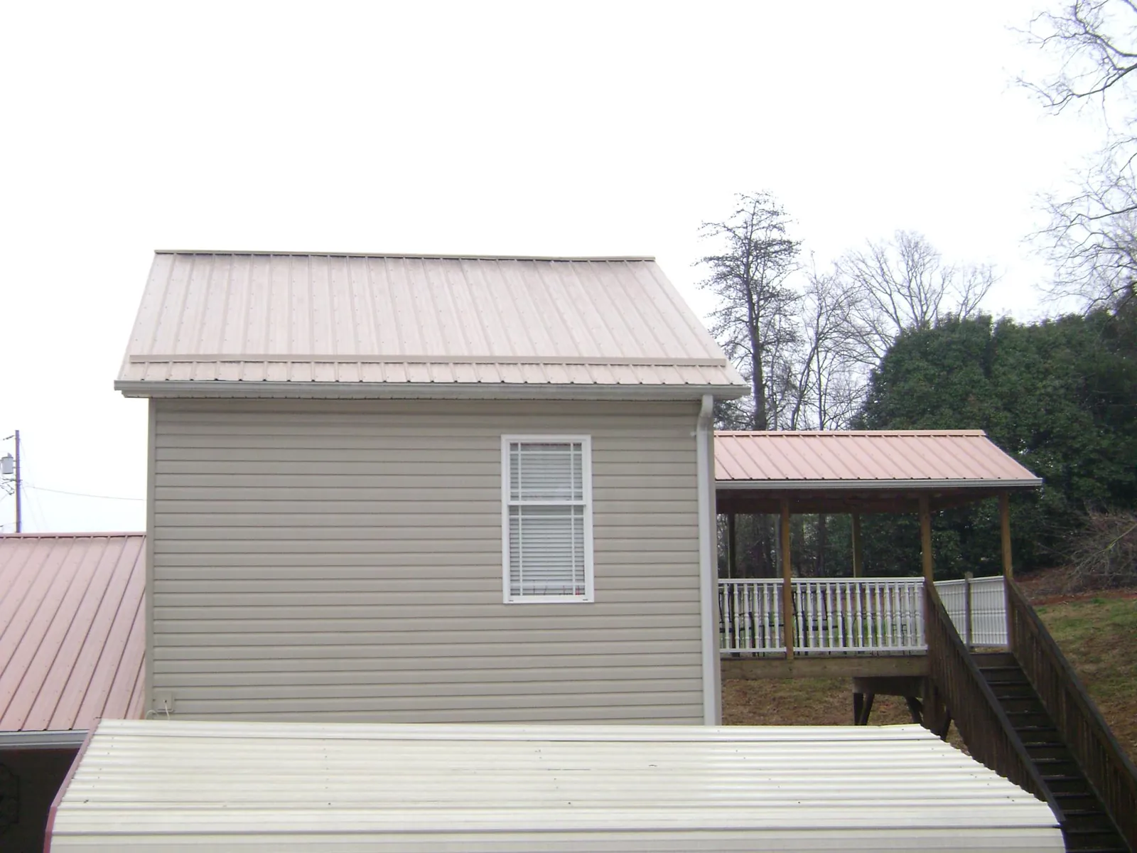 Tan metal roofs on a two story addition and attached porch, from a Roof Replacement job in Marlton