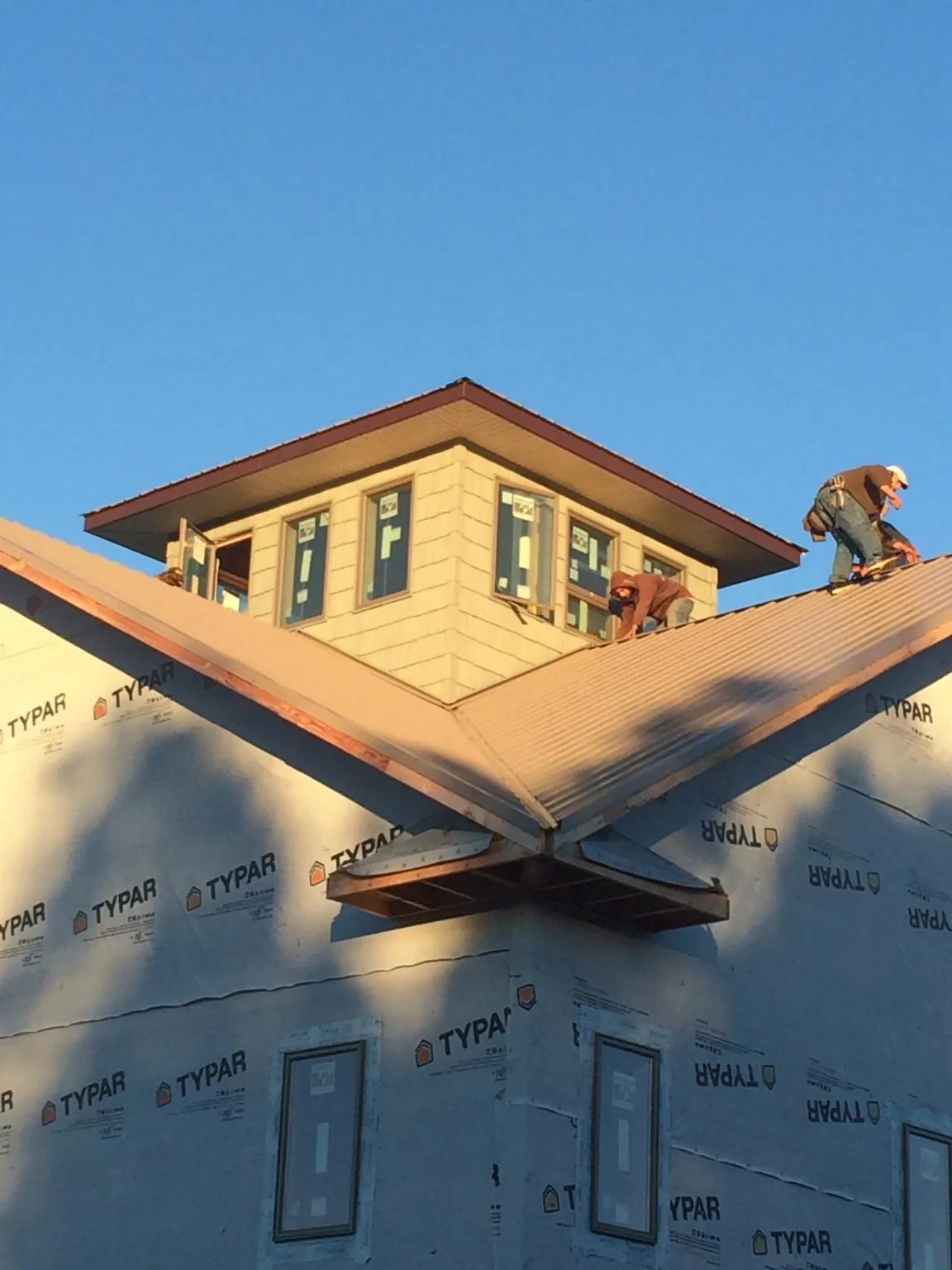 Roofers working around a rooftop cupola on a new metal roof at sunset — Roof Waterproofing in Marlton by Roofing Brothers
